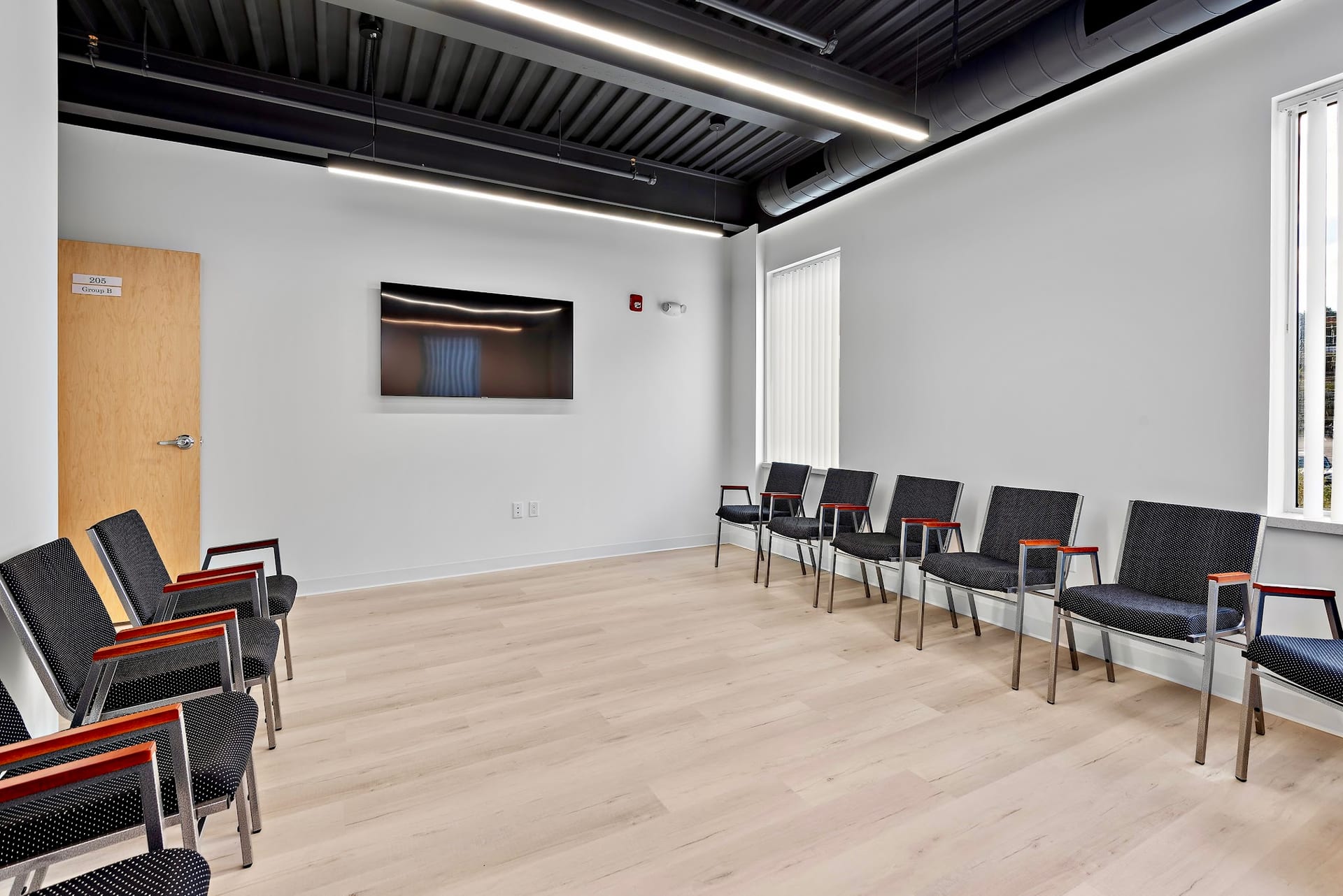 Group therapy room with chairs arranged in a semicircle and wall-mounted TV