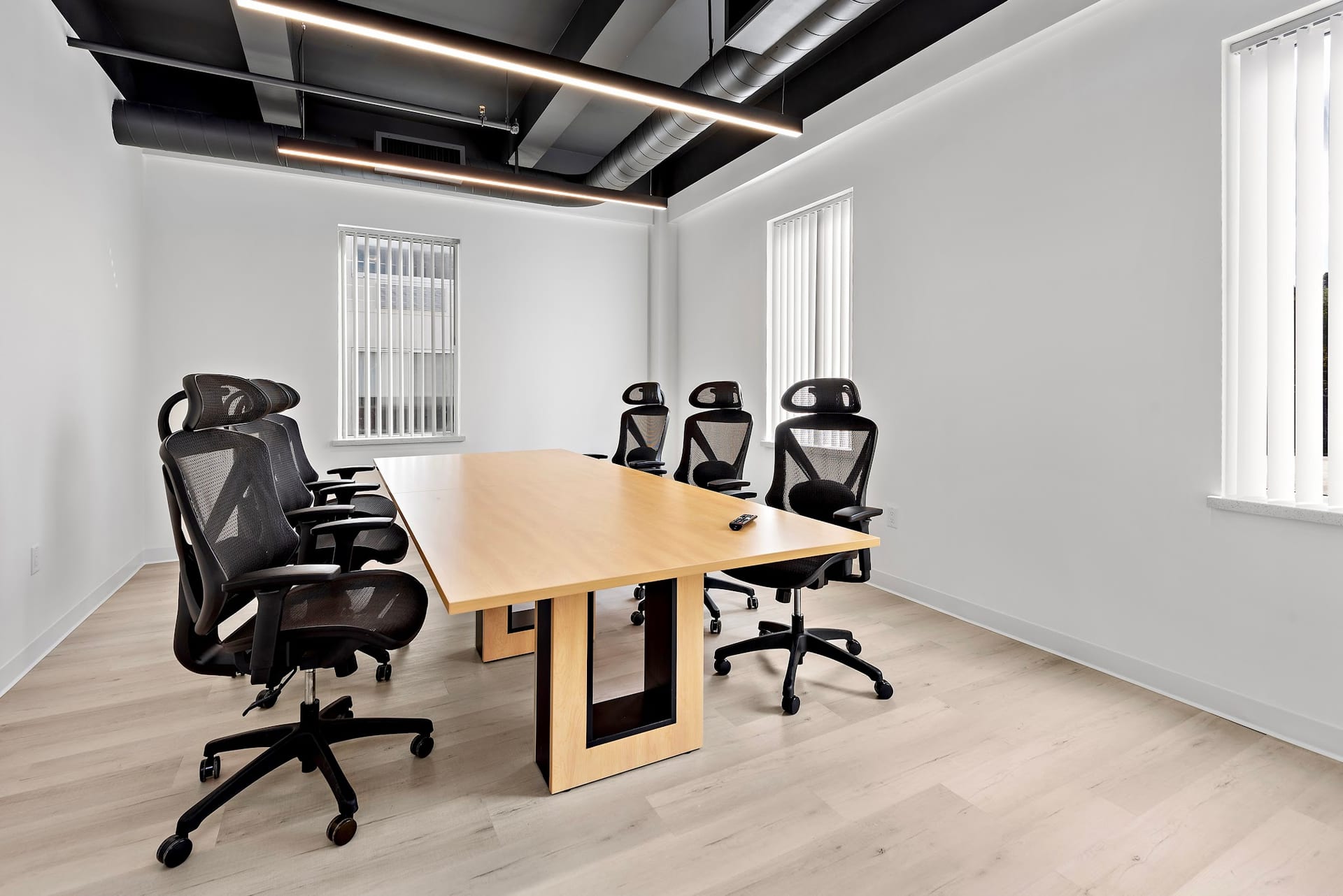 Modern conference room with wooden table and black ergonomic chairs